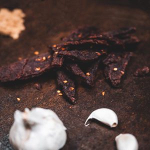 Jerky on brown table with garlic and spice