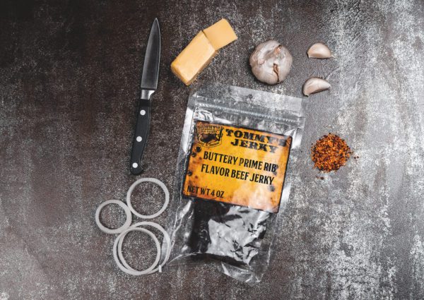 Beef jerky in bag with onion, garlic, spices, and cheese with knife