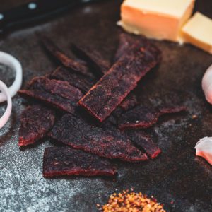 Beef jerky with onion, garlic, spices, and cheese with knife